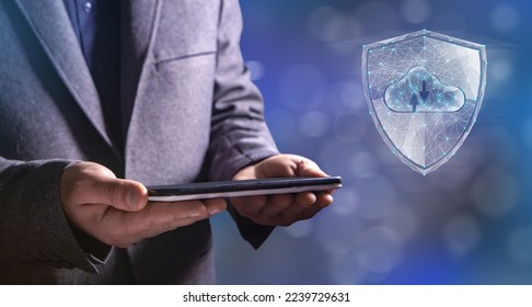 Shield and cloud storage from the web. Cyber security concept. Man holding a tablet in his hand