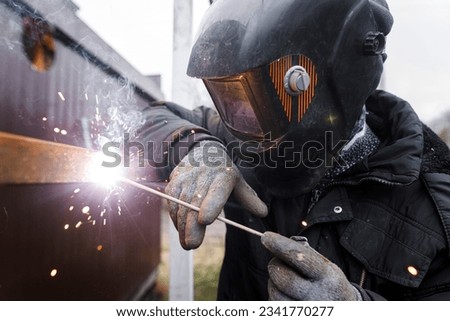 Shielded metal arc welding. Worker welding metal with electrodes, wearing protective helmet and gloves. Close up of electrode welding and electric sparks