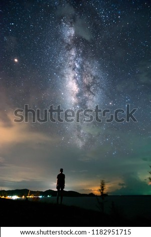 shilloute . A person is standing next to the Milky Way galaxy pointing on a bright star.


