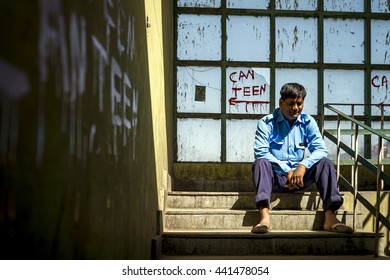 SHIMLA, INDIA - Jun 04, 2016: Security worker rest on the staircase of carpark with scribbled words on the wall.