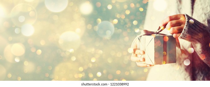 Shimmer background with snow, light bokeh. Woman hands opening gift box. Christmas, new year, birthday concept. Banner, copy space. - Powered by Shutterstock