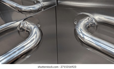 Shimmering metallic elevator pull handles with mirrorlike reflections