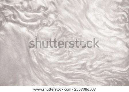 Shimmering silver abstract background. Liquid glitter paint texture waves and swirls. Beautiful shiny white glitter texture. Metallic silver paint close-up as a holiday background.