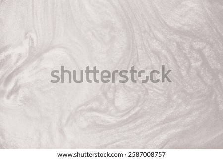 Shimmering silver abstract background. Liquid glitter paint texture waves and swirls. Beautiful shiny white glitter texture. Metallic silver paint close-up as a holiday background.