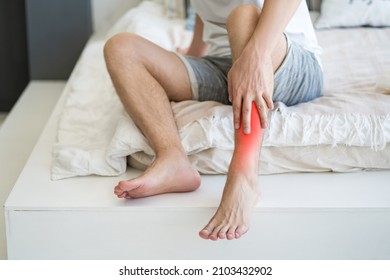 Shin pain, man suffering from ache and doing self-massage at home, self-soothing massaging - Shutterstock ID 2103432902