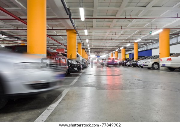 The shined underground garage with the moving cars\
and parked cars