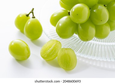 A lot of Shine-Muscat grapes and cut Shine-Muscat grapes on a white background. White grapes.  Japanese grapes. 
