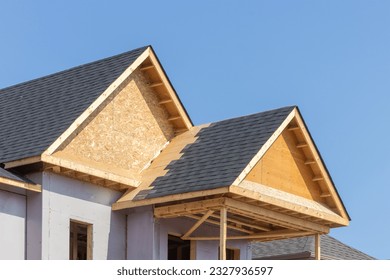Shingle covered dormers of a residential construction project showing plywood roof and oriented strand board or chip board dormer sheathing - Shutterstock ID 2327936597