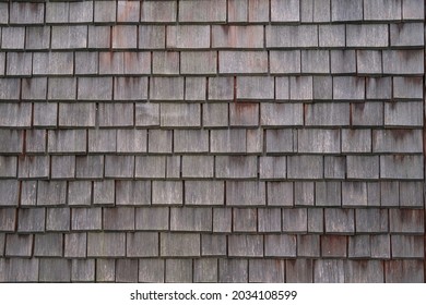 Shingle wooden tile facade background.Texture of old weathered wooden tiled roof or surface of natural veneer wall backdrop. Eco background. Environmental conservation,eco-friendly house concept