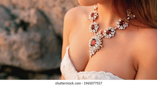 Shining large necklace with white and red crystals on the bride's chest, close-up 