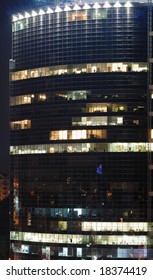 Shining skyscraper by night, pattern of rectangular windows running light