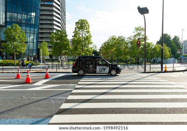 Shinjuku City, Tokyo, Japan - June\
12, 2021: Tokyo 2020 Olympic Games. Toyota taxi car passing in\
front of Japan Sport Olympic Square, Japan Olympic\
Museum.