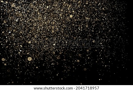 Shinny gold glitter texture abstract background. Defocused dots reflecting light against black.