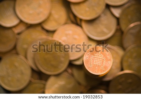 Shinny one penny against blurred 1 and 2 pence coins