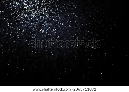 Shinny small particles glittering. Abstract texture on black background. Reflecting light.