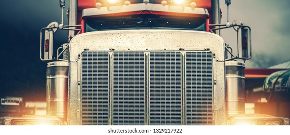 Shiny American Semi Truck On A Road. Large Chromed Grill Front View In Wide Format. Trucker On The Road.