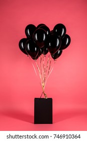 Shiny Black Balloons And Shopping Bag Isolated On Pink