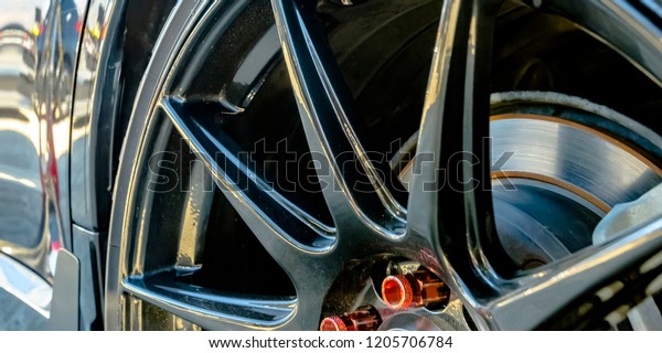 Shiny black car\
with black rim and red lug\
nuts