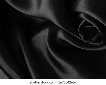 Shiny black crumpled fabric background. Liquid wavy shape.