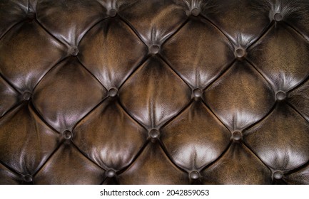 Shiny brown Chesterfield leather surface of an old couch