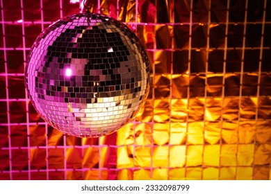 Shiny disco ball against foil party curtain under pink and orange light. Space for text - Powered by Shutterstock