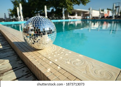 Shiny Disco Ball On Edge Of Swimming Pool. Party Decor