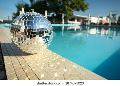 Shiny Disco Ball On Edge Of Swimming Pool. Party Decor