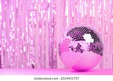 Shiny disco ball on table against blurred background, toned in pink. Space for text - Powered by Shutterstock