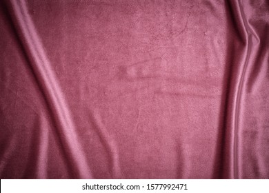 Shiny draped velour background. Wrinkled luxurious rose red cloth background. Soft red plush fabric with drapery. Smooth elegant purple pink silk velvet or satin texture. 