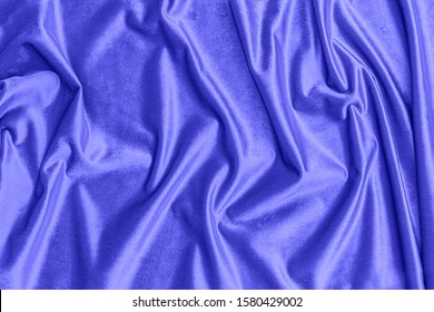 Shiny draped velour background. Wrinkled luxurious midnight blue cloth background. Soft phantome blue plush fabric with drapery. Smooth elegant silk velvet or satin texture. 