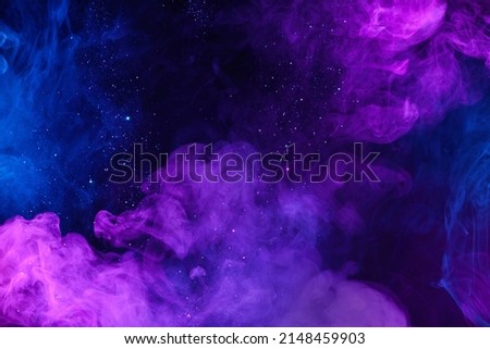 Shiny glitter particles in clouds of pink and blue colorful smoke abstract background