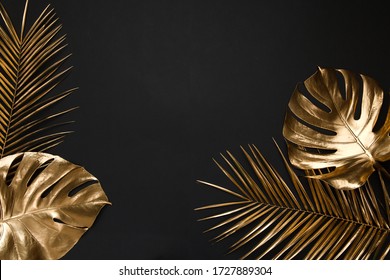 Shiny glossy golden painted tropical date palm and monstera leaves creatively arranged on black paper background. Empty space for copy, room for text. Trendy luxury border frame flatlay design. - Shutterstock ID 1727889304