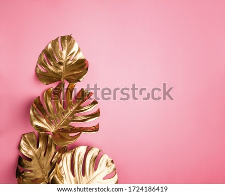 Shiny golden painted tropical monstera leaves bouquet on abstract pastel pink background isolated. Copy space. Fashionable glam floral arrangement.