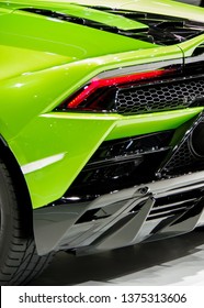 Shiny green sports car body tail light and exhuast pipe grid close up view