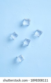 Shiny ice cubes and water drops on blue background. Top view.