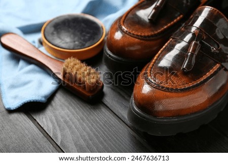 Shiny leather shoes, cloth, brush and shoe polish on black wooden background