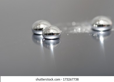 Shiny Mercury Drops On A Metal Background