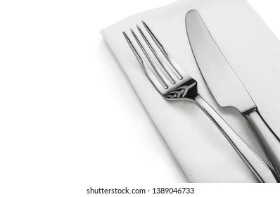 A Shiny Metal Fork And A Table-knife Lying On A Napkin In A White Background