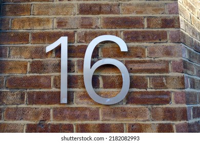 Shiny Metal Number Sixteen On A Red Brick Wall