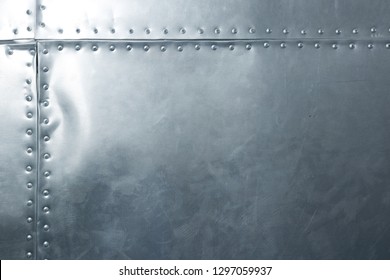 Shiny metal plate with rivets, riveted aluminum sheet with horizontal and vertical rows of rivets along seams, a military background