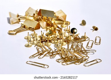 Shiny paper clips and buttons made of yellow metal on a white background. Office and school accessories. Selective focus