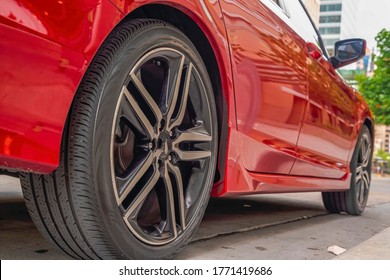 Shiny Red Car Exterior With Close Up Of The Black Rubber Wheels Against Road