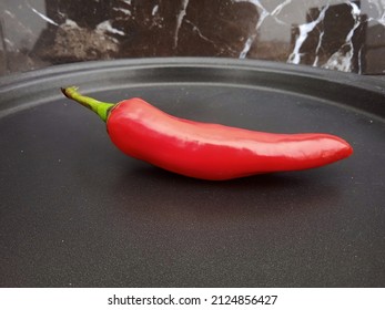 Shiny Red Chilli Pepper Ona Black Tray With A Black Background. Useful For Kitchen Items Or Spices Related Content. 