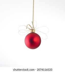 Shiny red Christmas bauble held with gold glittery ribbon - Shutterstock ID 2074116533