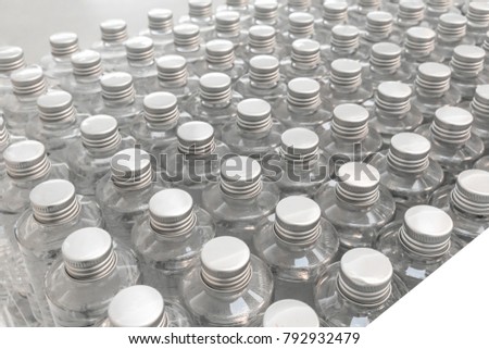 Shiny silver caps of clear plastic bottles in rows for pattern background. Top view.