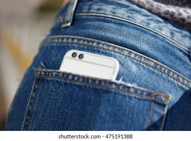 Shiny silver mobile phone with dual camera in pocket of blue jeans. close up macro. Buy  super new phone model, best new smart phone of the year. New super camera with two lenses