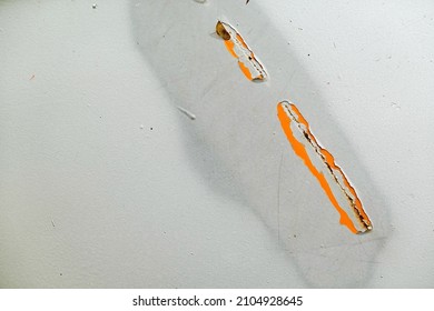 The Shiny Silver-painted Steel Sheet Peels Off And Decays Until The Inside Is Visible Orange.  It's A Scratch That Has Been Painted Over To Fix It.