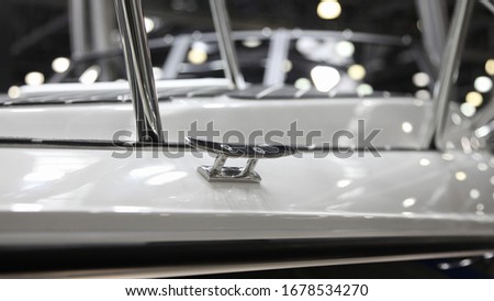 Shiny stainless mooring cleat on white motor boat deck close up, marine equipment
