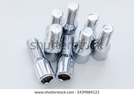 shiny steel chrome coated wheel bolts on white background, full-frame closeup high angle view, real photo