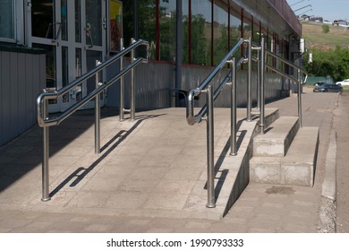 Shiny steel handrails at the entrance to the store. Handrails and ramp for disabled people.